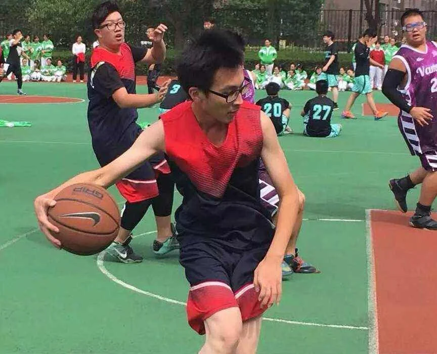 Student in red jersey dribbling at a school basketball game