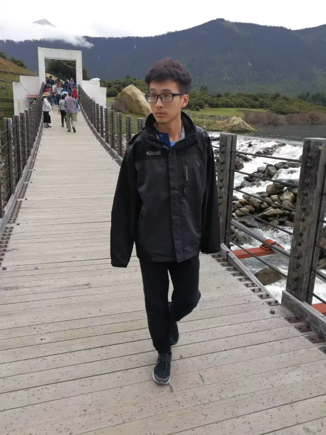 Teen walking a wooden bridge by a lake in Nyingchi