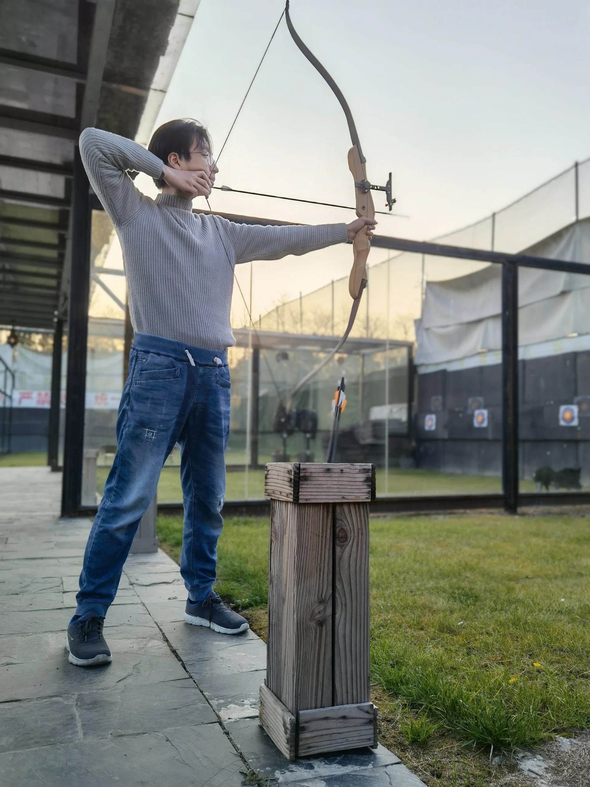 Teen drawing a bow at an archery range
